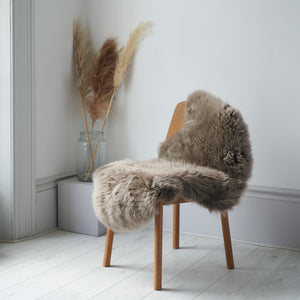 Ethically crafted  Sheepskin rug in Taupe draped over a chain 